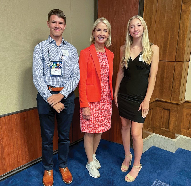 Two teenagers standing with Congresswoman Miller