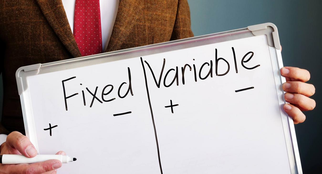 Man holding a marker white board with Fixed and Variable columns written on it in black